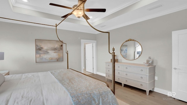 bedroom with crown molding, a tray ceiling, ceiling fan, and hardwood / wood-style flooring