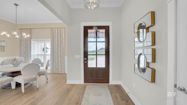 entryway featuring light hardwood / wood-style flooring, ornamental molding, and a chandelier