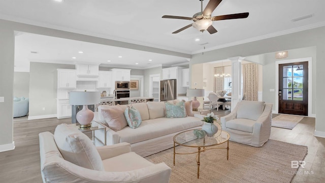 living room featuring crown molding, ceiling fan with notable chandelier, and light hardwood / wood-style floors