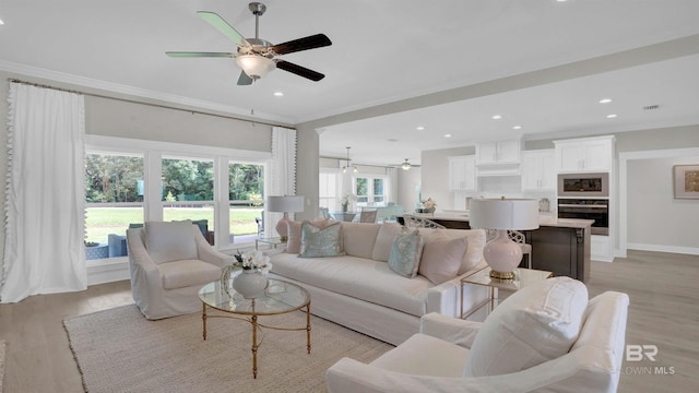 living room with ornamental molding, light hardwood / wood-style floors, and ceiling fan