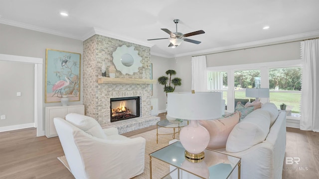 living room with ornamental molding, a brick fireplace, ceiling fan, and light hardwood / wood-style floors