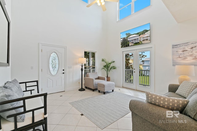 tiled living room featuring ceiling fan, french doors, and a high ceiling