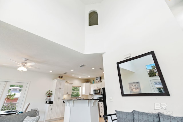 kitchen with kitchen peninsula, a kitchen bar, plenty of natural light, and white cabinetry