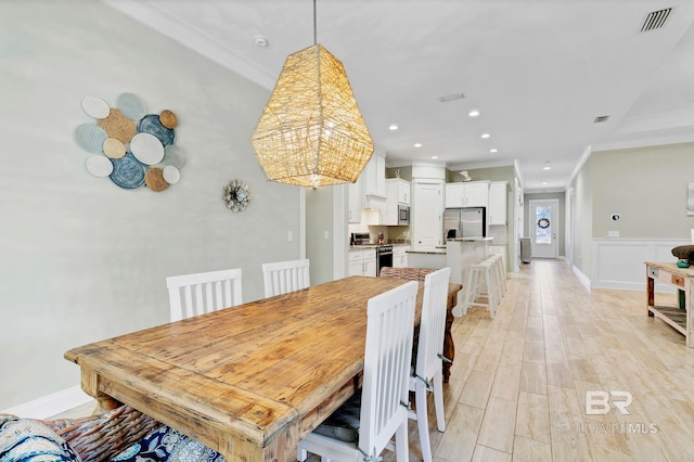 dining room with recessed lighting, a wainscoted wall, visible vents, light wood-style floors, and crown molding