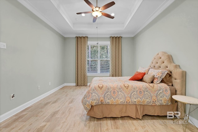 bedroom with baseboards, a tray ceiling, crown molding, and wood finished floors