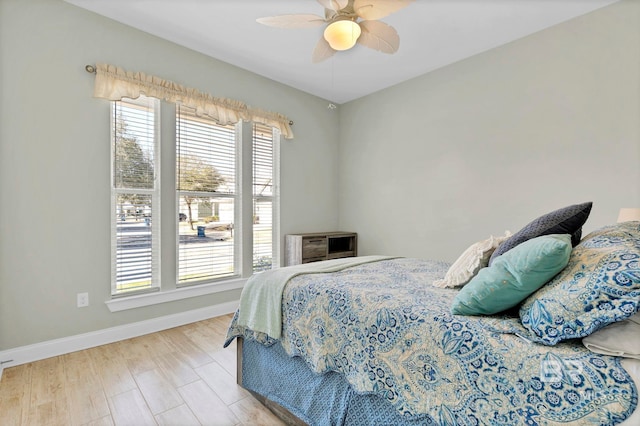 bedroom featuring wood finished floors, a ceiling fan, and baseboards