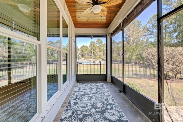 unfurnished sunroom with ceiling fan, a wealth of natural light, and wood ceiling