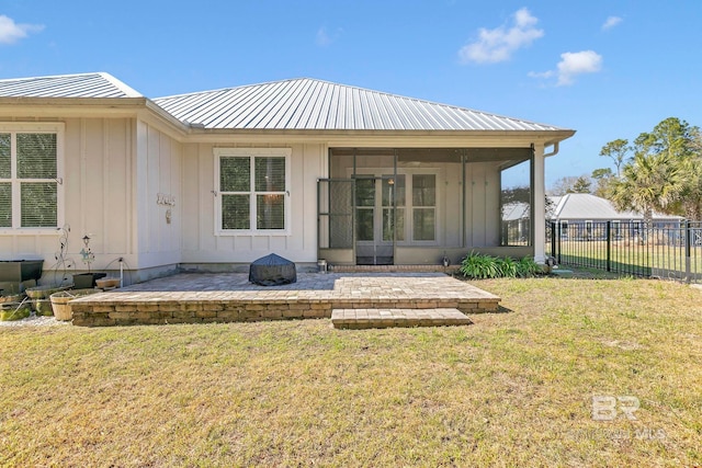 back of house with a sunroom, metal roof, fence, a yard, and board and batten siding