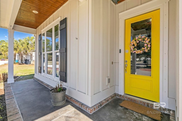 view of exterior entry featuring a porch and board and batten siding