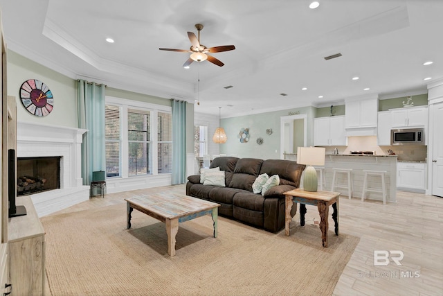 living room with visible vents, a tray ceiling, and crown molding