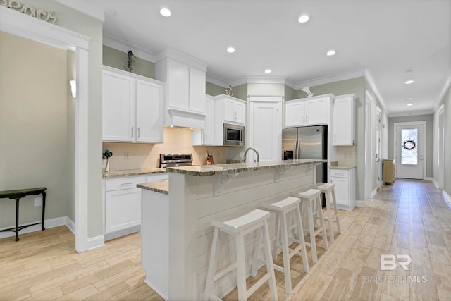 kitchen with white cabinetry, stainless steel appliances, and backsplash