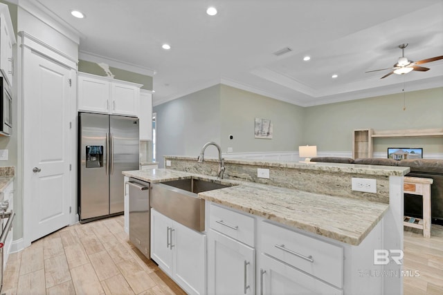 kitchen featuring stainless steel appliances, visible vents, ornamental molding, white cabinetry, and a sink