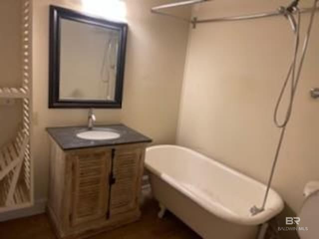 full bath with a freestanding bath, vanity, and toilet