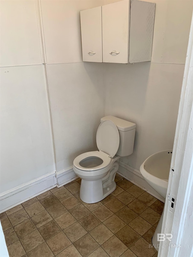 bathroom featuring baseboards and toilet