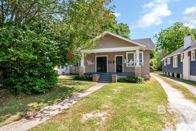 bungalow with covered porch and a front yard