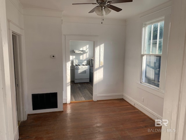 empty room with ceiling fan, visible vents, baseboards, ornamental molding, and hardwood / wood-style floors