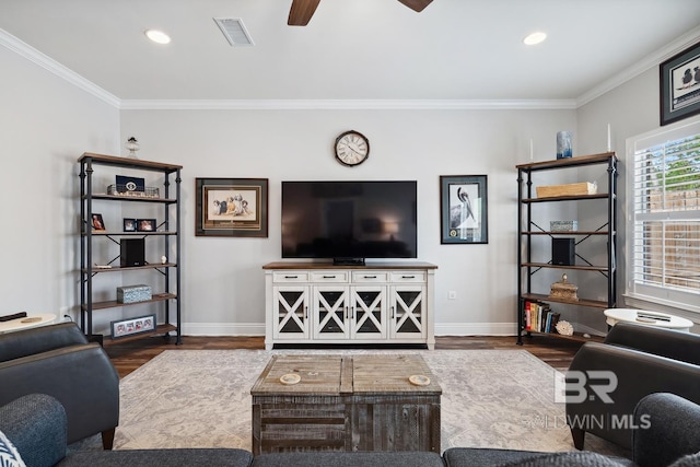 living room with ornamental molding, visible vents, a ceiling fan, and wood finished floors