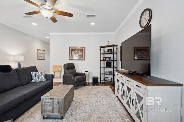 living room with visible vents, wood finished floors, ornamental molding, and a ceiling fan