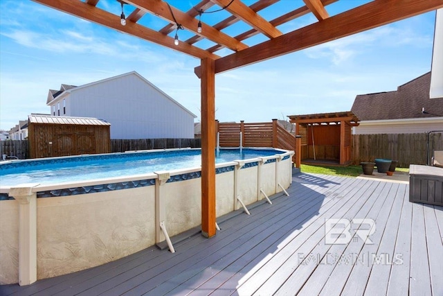 wooden deck with a fenced in pool, fence, a pergola, and an outbuilding