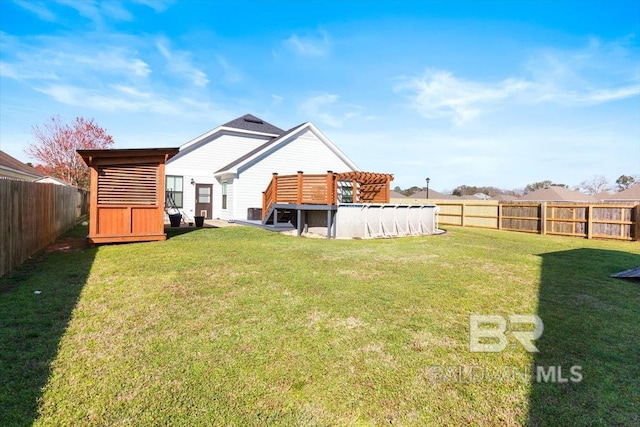 back of property with a yard, a fenced backyard, a wooden deck, and a fenced in pool