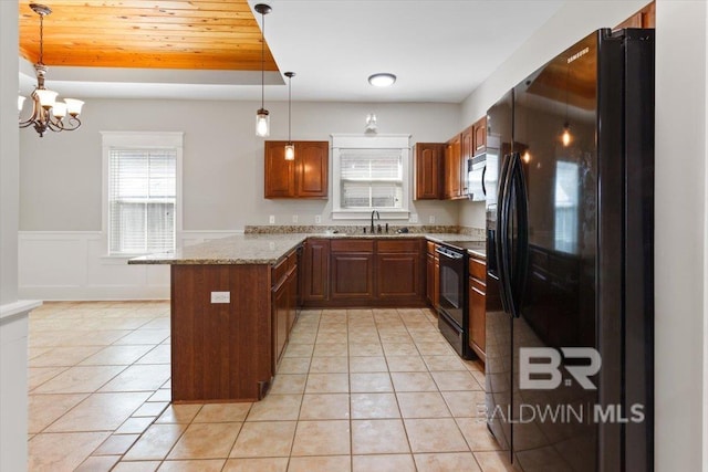 kitchen with light tile patterned floors, a peninsula, a sink, wainscoting, and black appliances