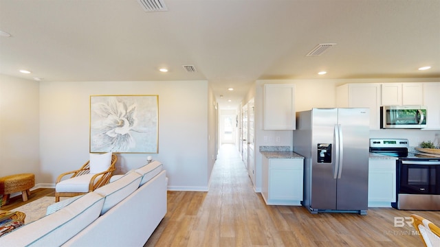 kitchen featuring light hardwood / wood-style flooring, light stone countertops, white cabinets, and appliances with stainless steel finishes