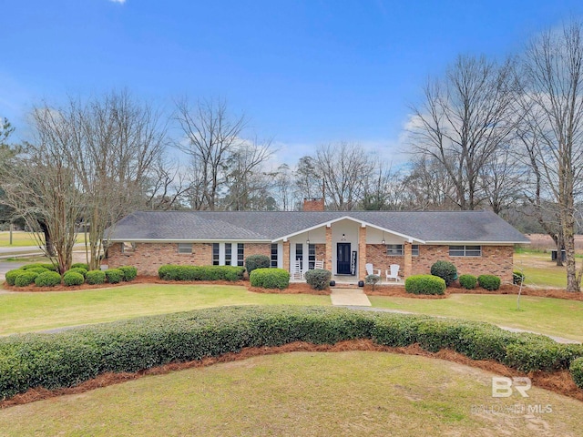 single story home with a chimney, a front lawn, and brick siding