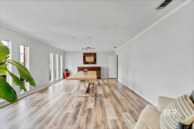 unfurnished dining area with light wood finished floors, baseboards, visible vents, and crown molding