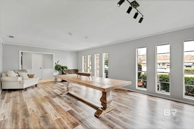 dining room with light wood-style flooring, visible vents, and crown molding