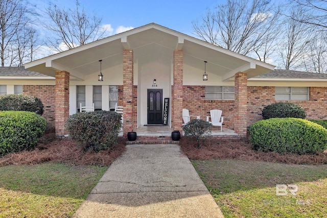 doorway to property with a porch and brick siding