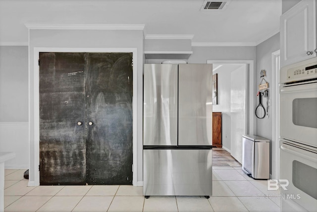 kitchen featuring light tile patterned floors, double oven, visible vents, ornamental molding, and freestanding refrigerator