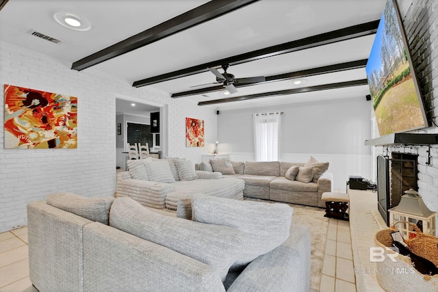 living room with a fireplace with raised hearth, brick wall, light tile patterned flooring, and visible vents