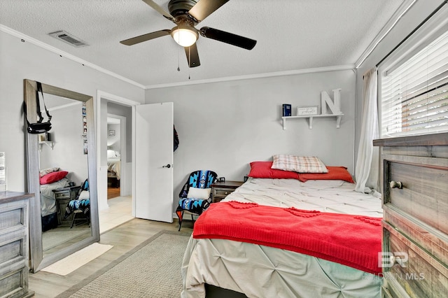 bedroom featuring crown molding, visible vents, a ceiling fan, a textured ceiling, and wood finished floors