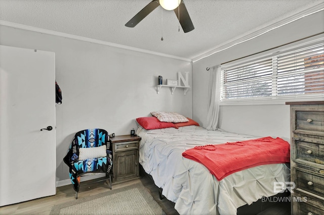 bedroom with a textured ceiling, ceiling fan, ornamental molding, and wood finished floors