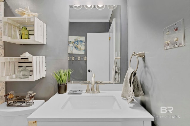 half bathroom featuring vanity, toilet, and crown molding