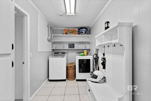 mudroom featuring light tile patterned flooring, washing machine and clothes dryer, and crown molding