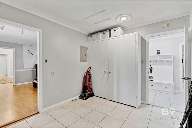 interior space with ornamental molding, attic access, light tile patterned flooring, electric panel, and baseboards