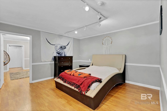 bedroom featuring ornamental molding, wood finished floors, and baseboards