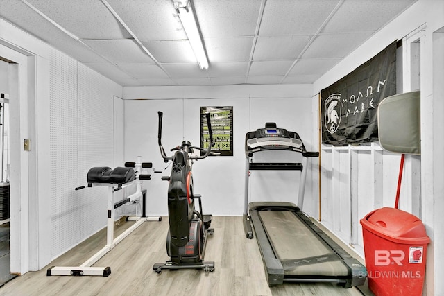 exercise room with a paneled ceiling and wood finished floors