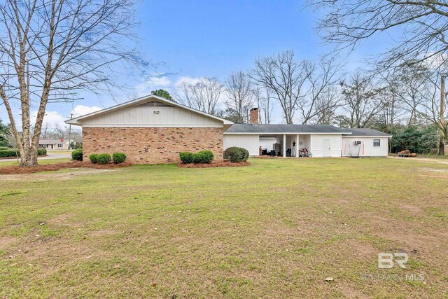 ranch-style house featuring a chimney, a front lawn, and brick siding