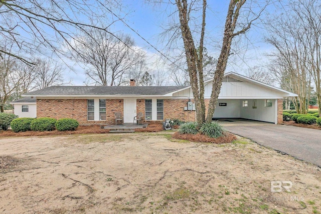 single story home with a carport, driveway, brick siding, and a chimney