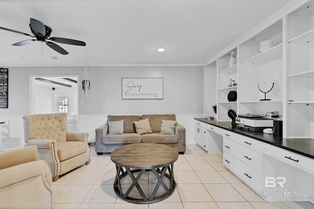 living room with light tile patterned floors, crown molding, a ceiling fan, and built in desk