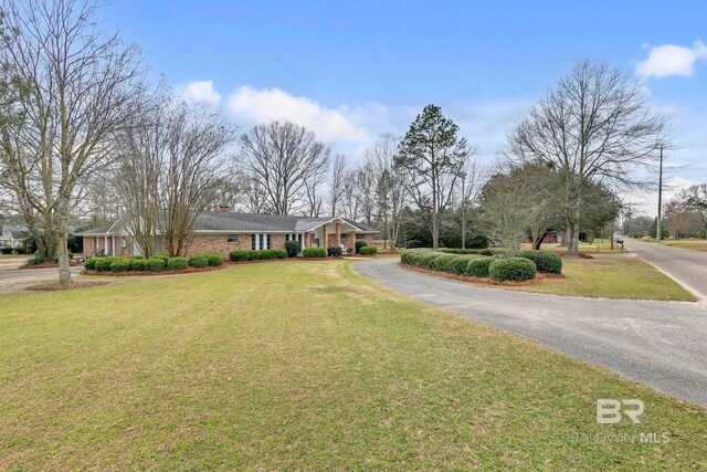 view of front of property featuring a chimney, a front lawn, and brick siding