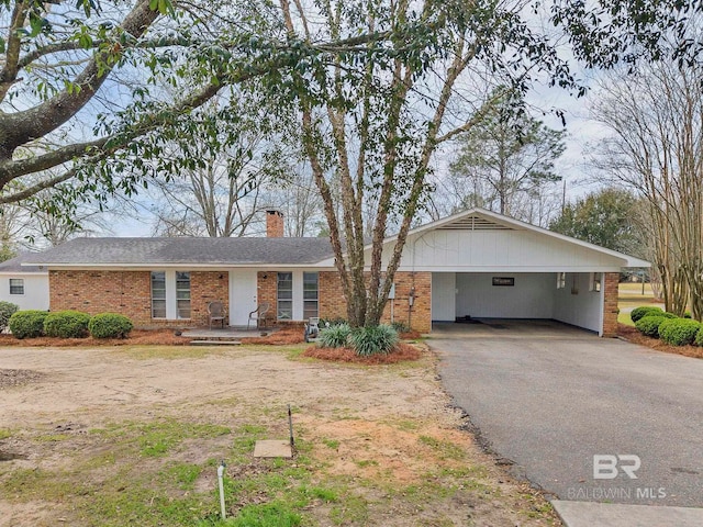 single story home featuring a chimney, aphalt driveway, and brick siding