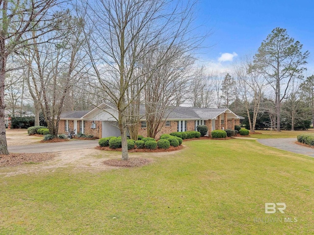 view of front facade with driveway, brick siding, and a front yard