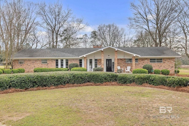 view of front of house with a chimney, a front lawn, and brick siding