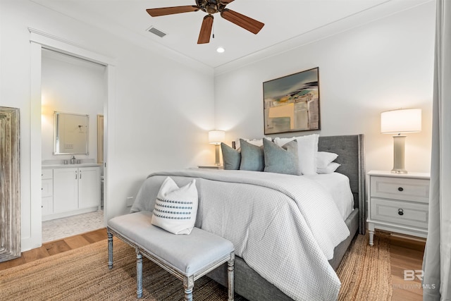 452 Colony Dr, Fairhope, AL 36532 - bedroom featuring wood finished floors, visible vents, ornamental molding, connected bathroom, and a sink