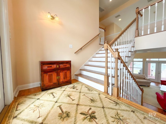 2210 W Beach Blvd, Gulf Shores, AL 36542 - staircase with visible vents, baseboards, wood finished floors, a high ceiling, and french doors