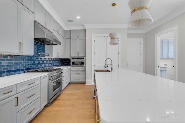 926 Inlet Cir, Gulf Shores, AL 36542 - kitchen with appliances with stainless steel finishes, under cabinet range hood, ornamental molding, backsplash, and light wood-style flooring