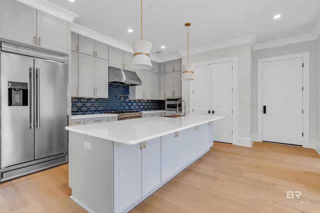926 Inlet Cir, Gulf Shores, AL 36542 - kitchen featuring high end fridge, under cabinet range hood, crown molding, light wood-style flooring, and tasteful backsplash
